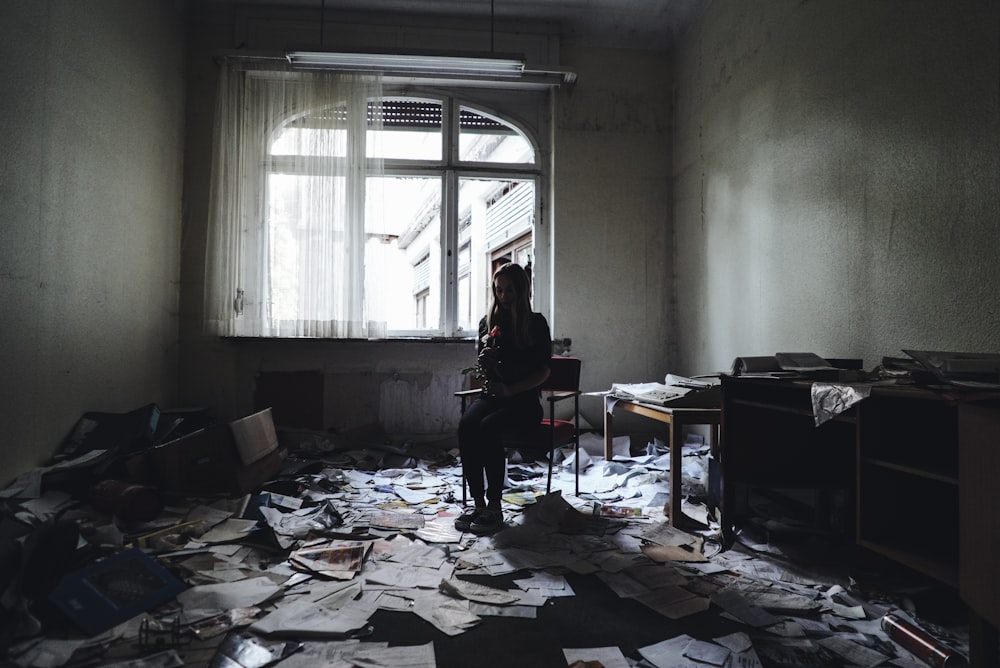 woman sitting on chair surrounded by papers on floor