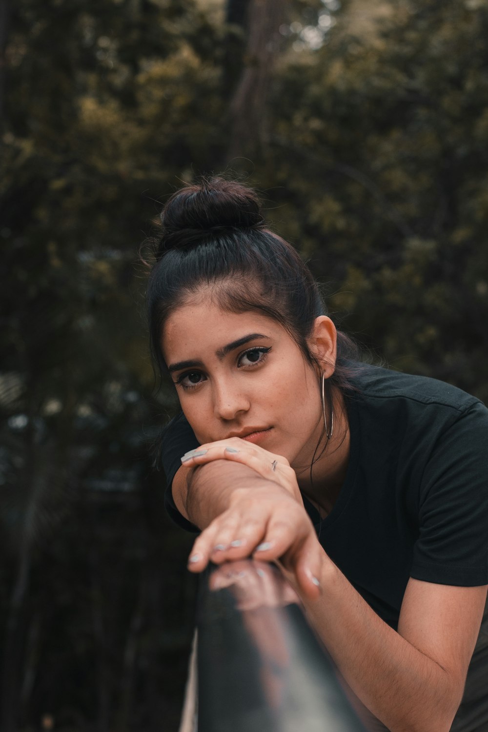 woman in black shirt resting arm and head on chrome metal railings