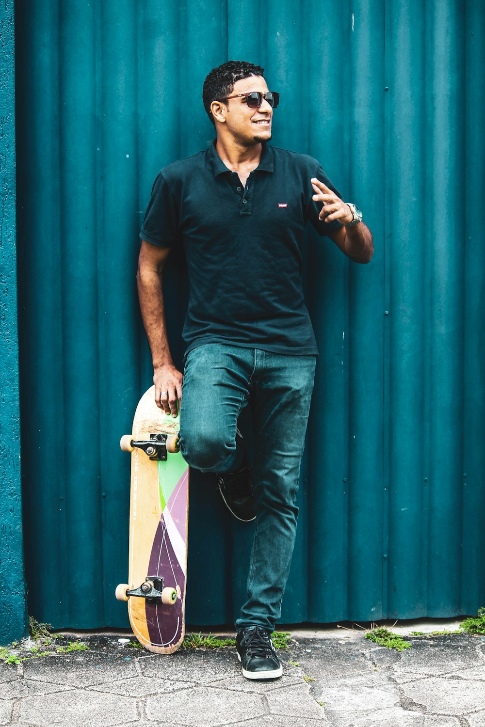 man in black polo shirt leaning with skateboard