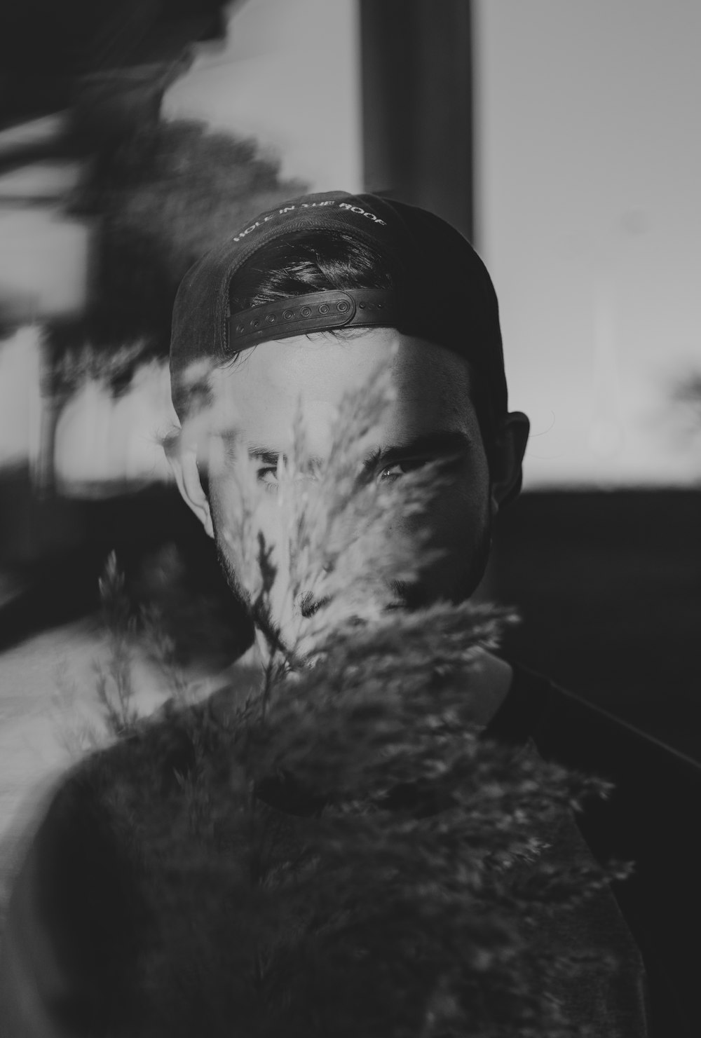 grayscale photography of man covered by plant