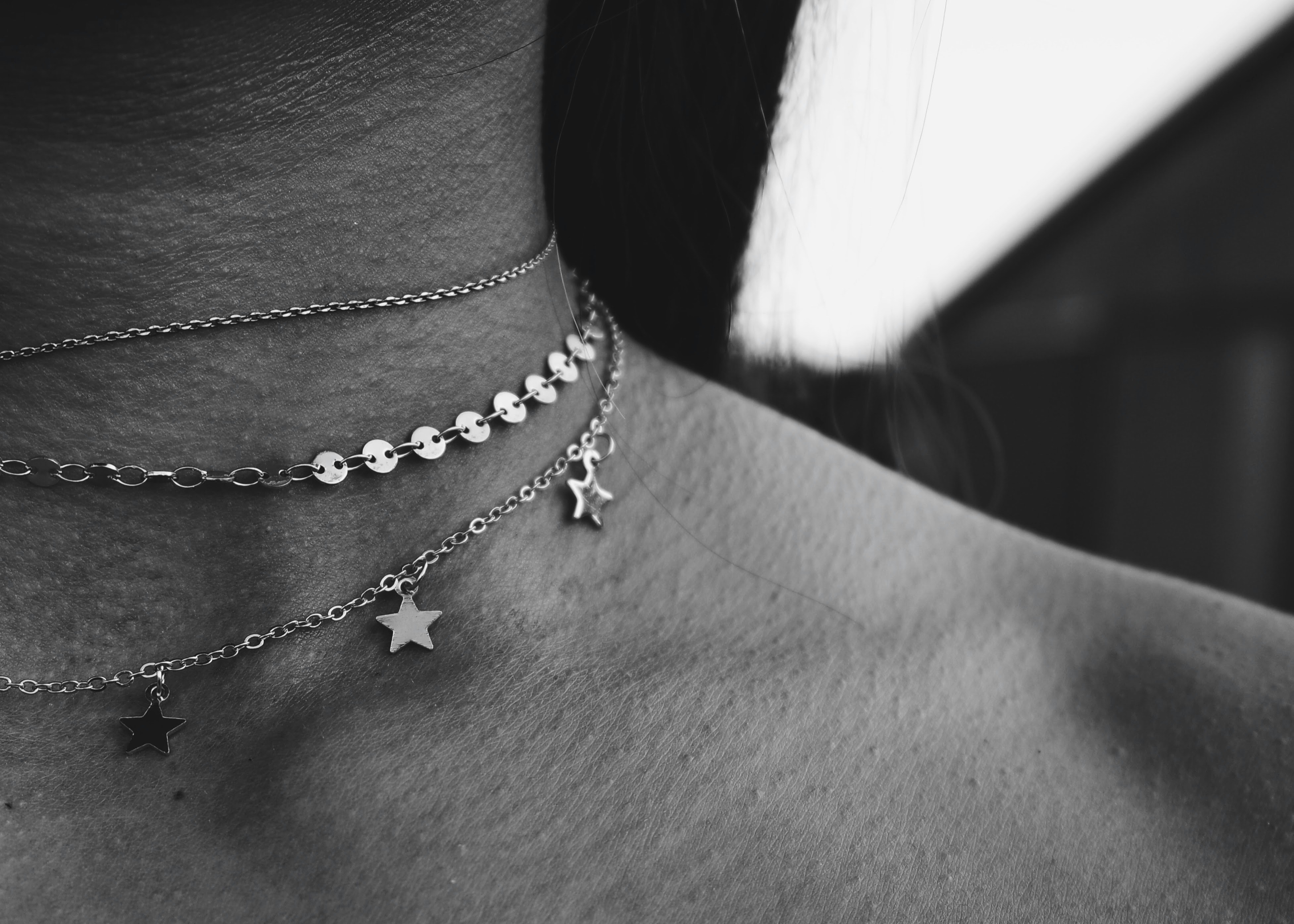 Silver star charm choker necklace on light pink fabric, jewelry close-up