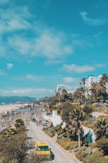 aerial photograph of yellow vehicle traveling on road near building during daytime