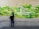 A person and a child interact with a colorful wall display, featuring green rectangular blocks of various sizes, some labeled with text. The display includes words like 'COMMUNITY' and 'COMUNIDAD' prominently. Orange and yellow flowers adorn the display, adding splashes of color.