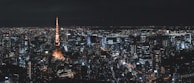 A panoramic cityscape of Tokyo at night, glowing with neon lights and bustling energy.
