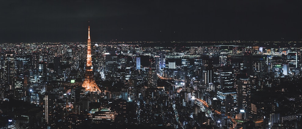 A panoramic view of Tokyo's skyline at sunrise, with Mount Fuji glowing softly in the distance and sleek glass skyscrapers bathed in warm golden light.