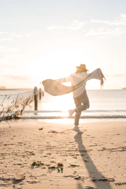 person in white sport shirt on shore during golden hour