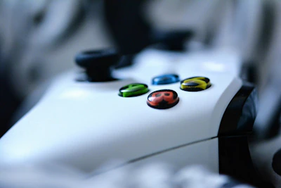 Close-up of a gamer holding a controller with colorful game graphics in the background.