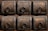 A detailed view of six ornate, square wooden panels, each featuring a decorative metal ring and intricate metalwork along the borders. The wood is dark with visible grain, complemented by the metallic embellishments which include small round studs and decorative patterns.