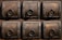A detailed view of six ornate, square wooden panels, each featuring a decorative metal ring and intricate metalwork along the borders. The wood is dark with visible grain, complemented by the metallic embellishments which include small round studs and decorative patterns.