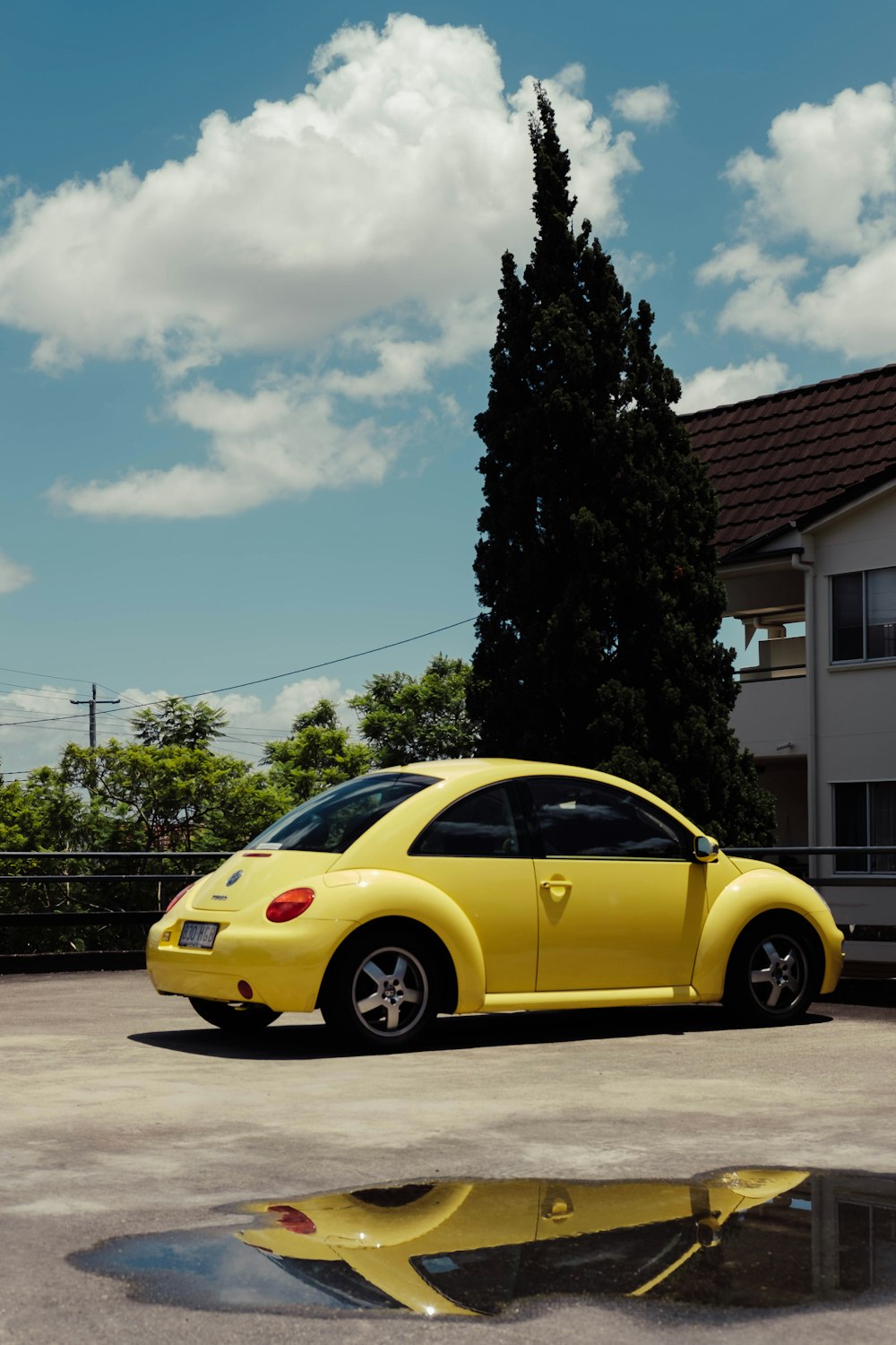 yellow Volkswagen Beetle parked beside house