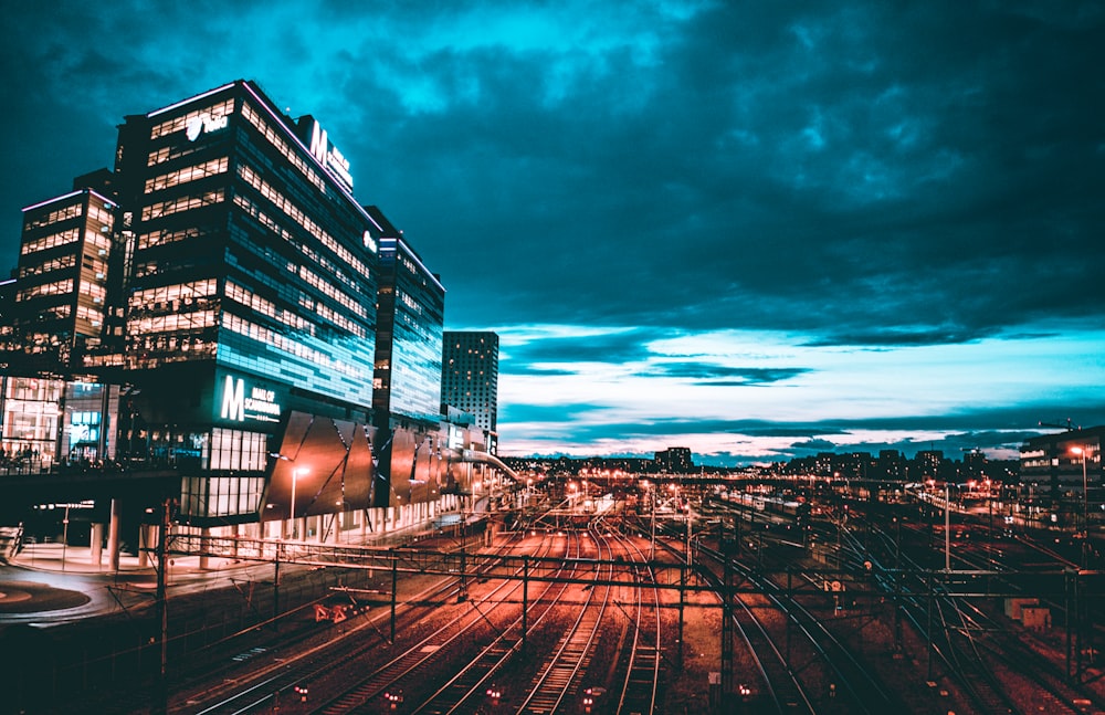 lighted buildings near railway at night