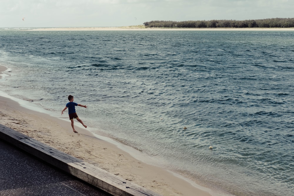 boy playing beside seashore