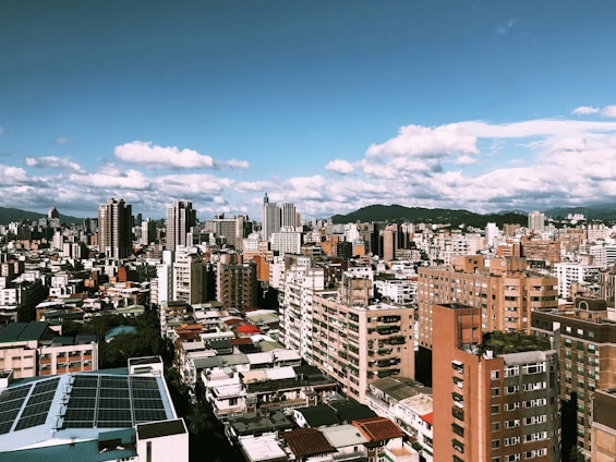 A vibrant cityscape of Hong Kong with green rooftops and solar panels under a clear blue sky.