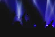 Close-up of a performer mid-set, glowing under subtle stage spotlights with a blurred audience behind.