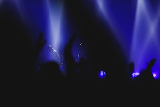 Close-up of a performer mid-set, glowing under subtle stage spotlights with a blurred audience behind.