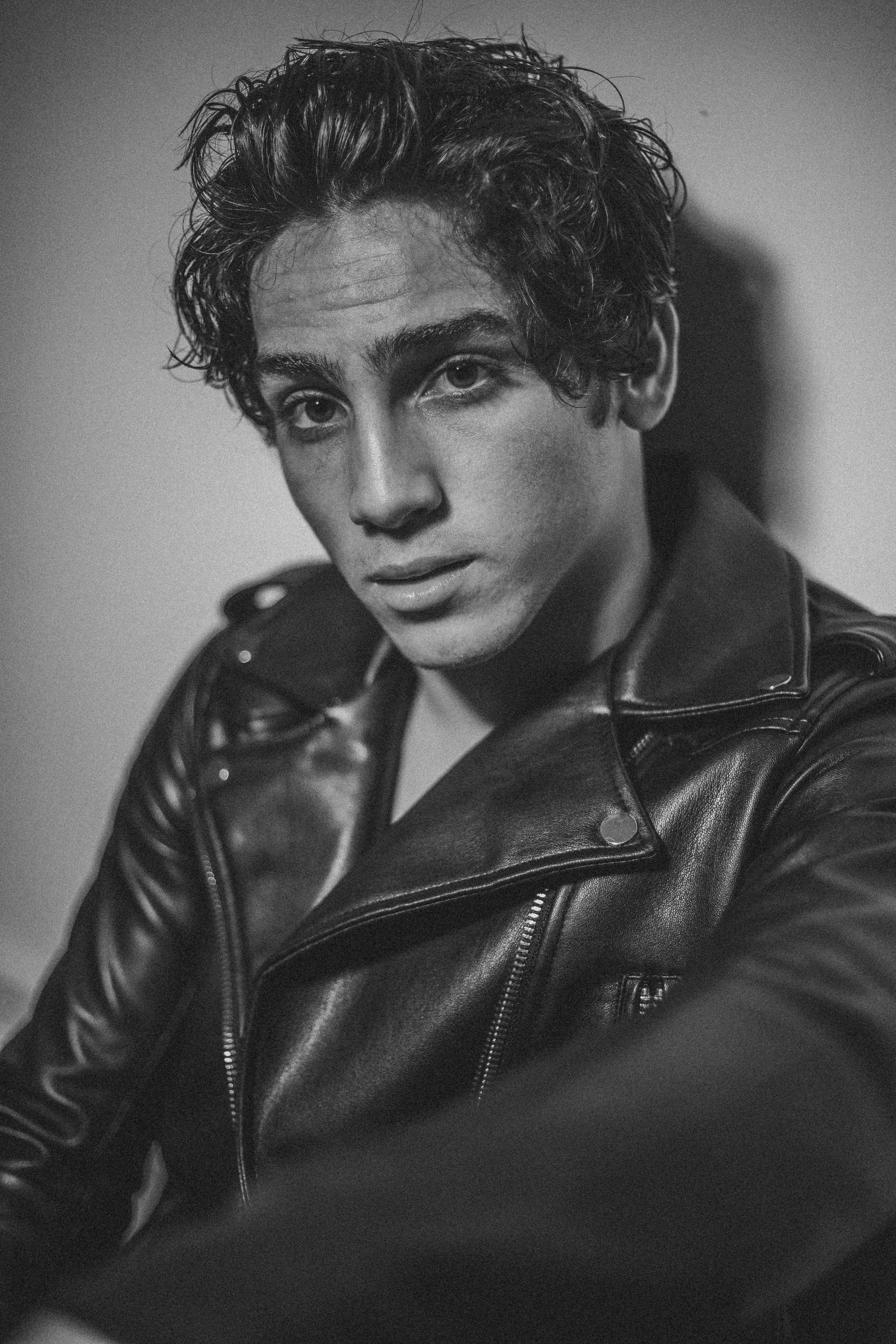 man wearing jacket leaning on wall