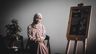 woman in pink long-sleeved dress near easel