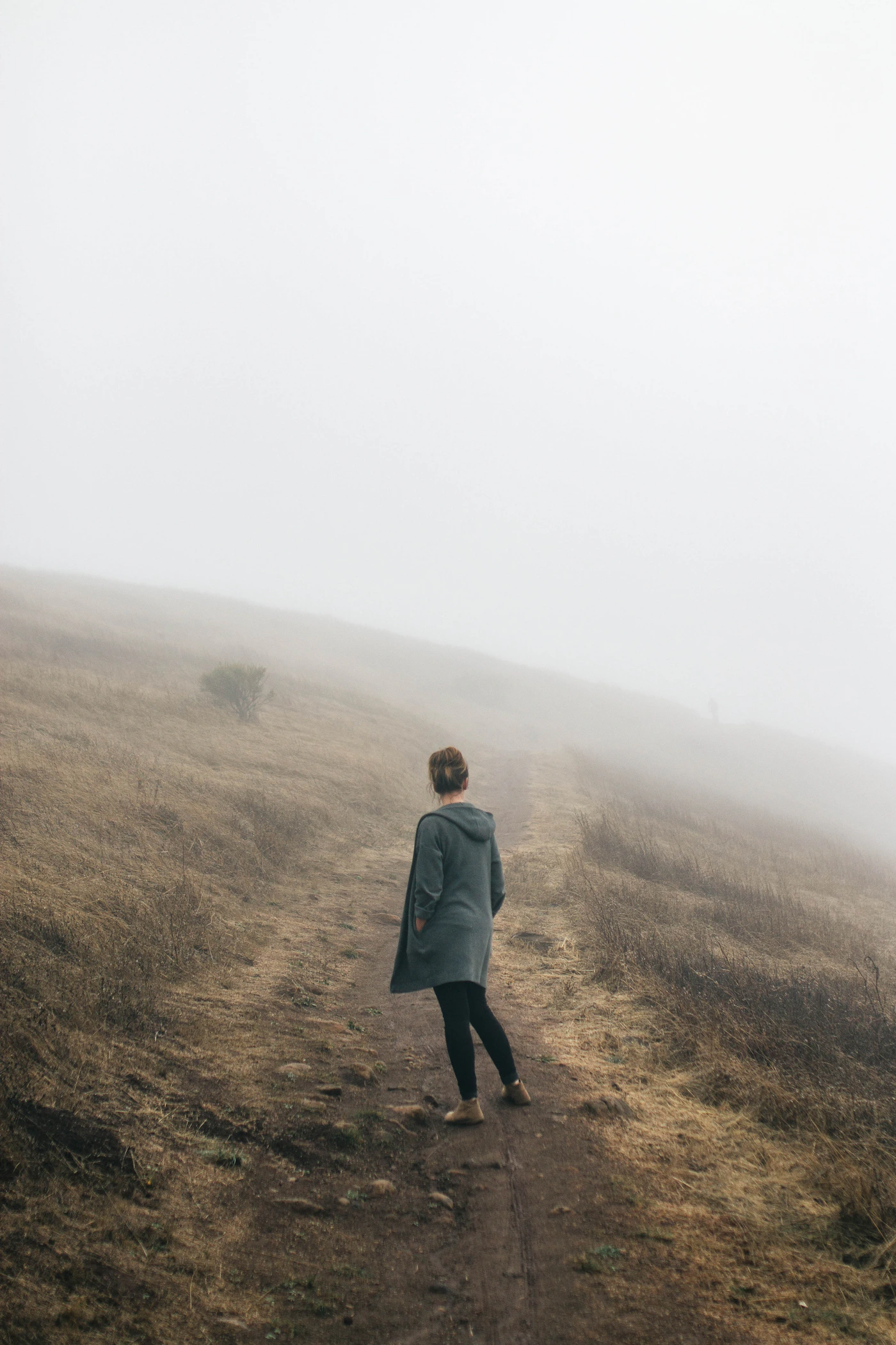 A lone walker standing on a quiet road in the fog