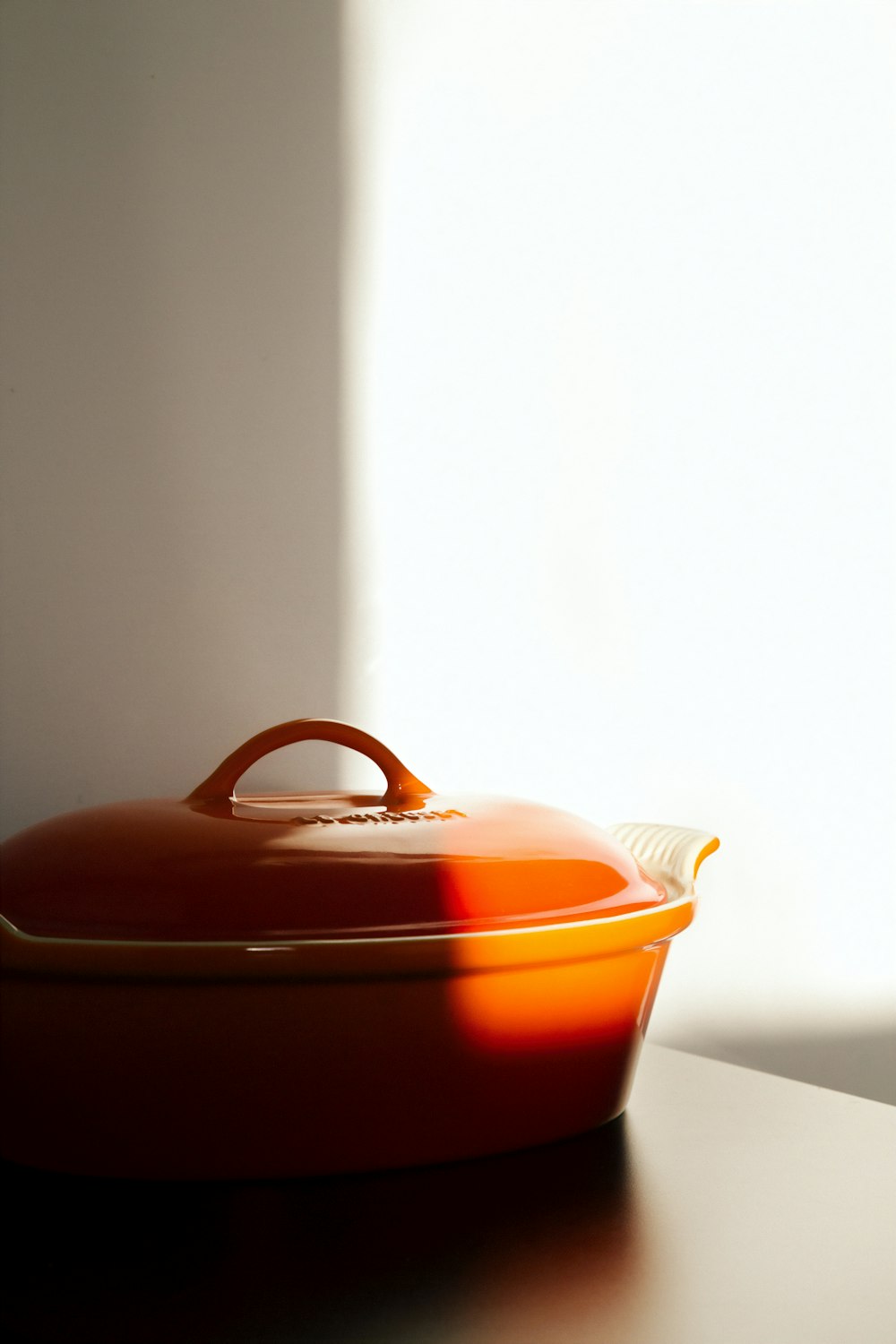 orange cooking pot on brown wooden surface
