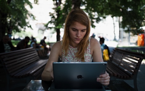 woman sitting on chair while using silver iPad