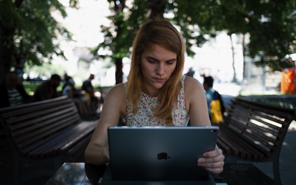 mulher sentada na cadeira enquanto usa iPad prateado