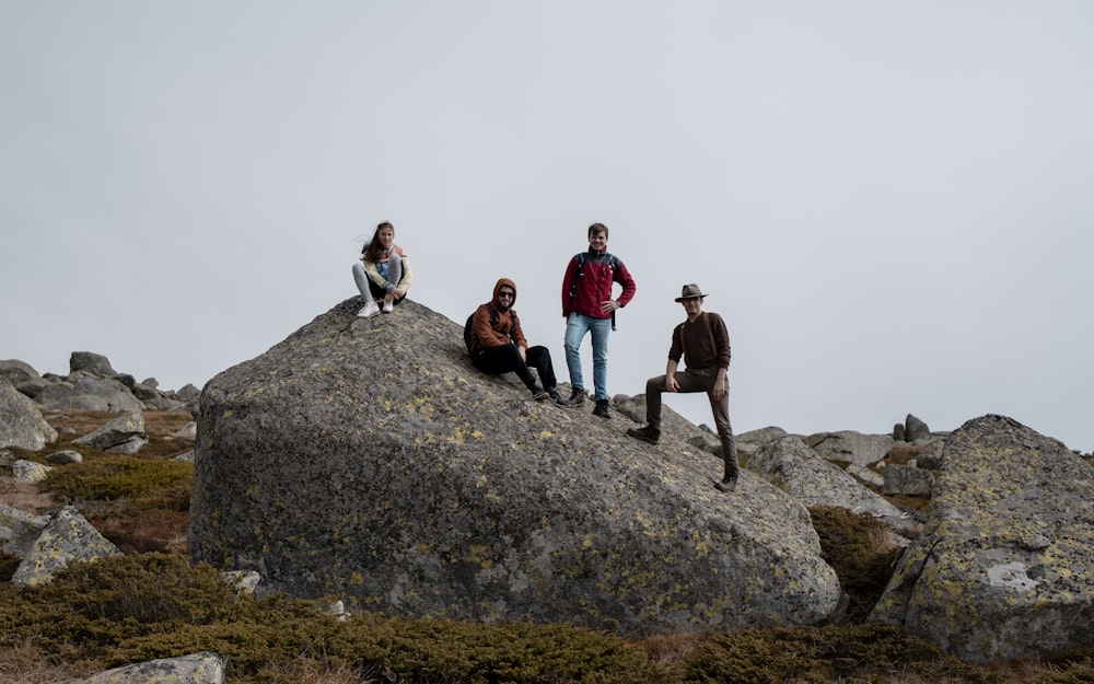 hombres y mujeres de pie y sentados en la roca
