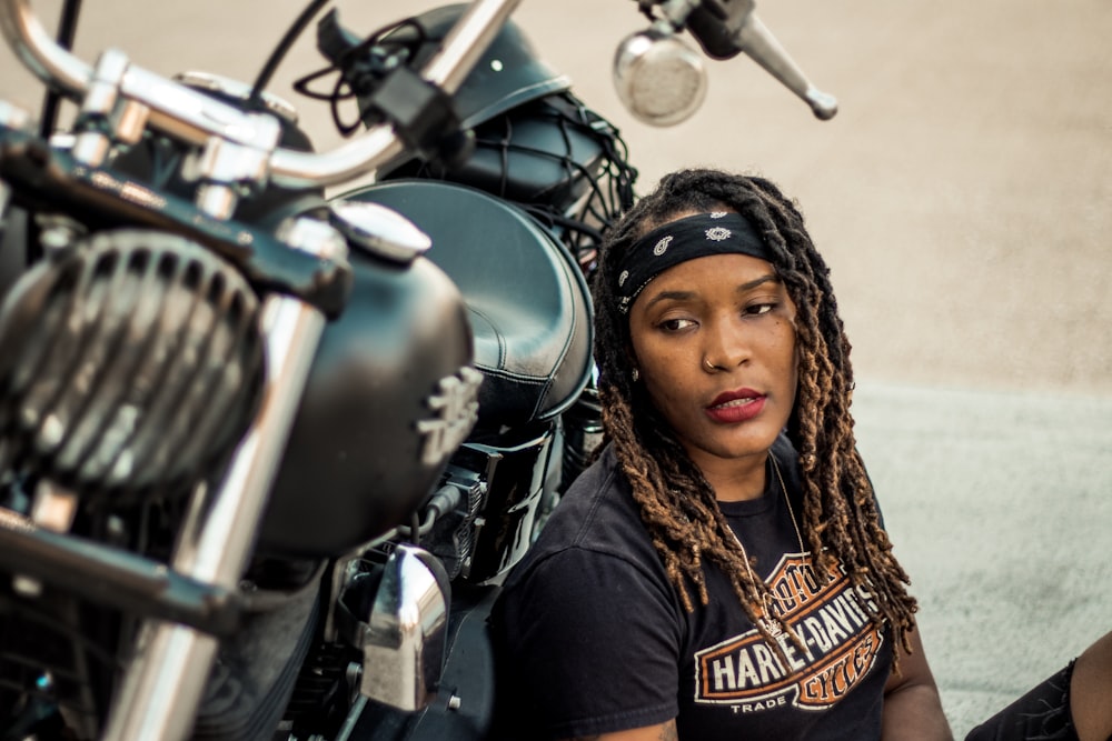 woman in black top leaning on motorcycle