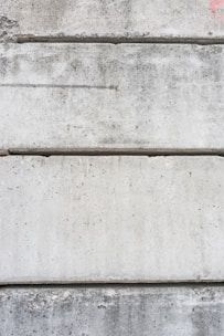 Several large, rectangular concrete slabs arranged horizontally, displaying a mottled gray texture with natural imperfections and speckles.