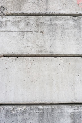 Several large, rectangular concrete slabs arranged horizontally, displaying a mottled gray texture with natural imperfections and speckles.
