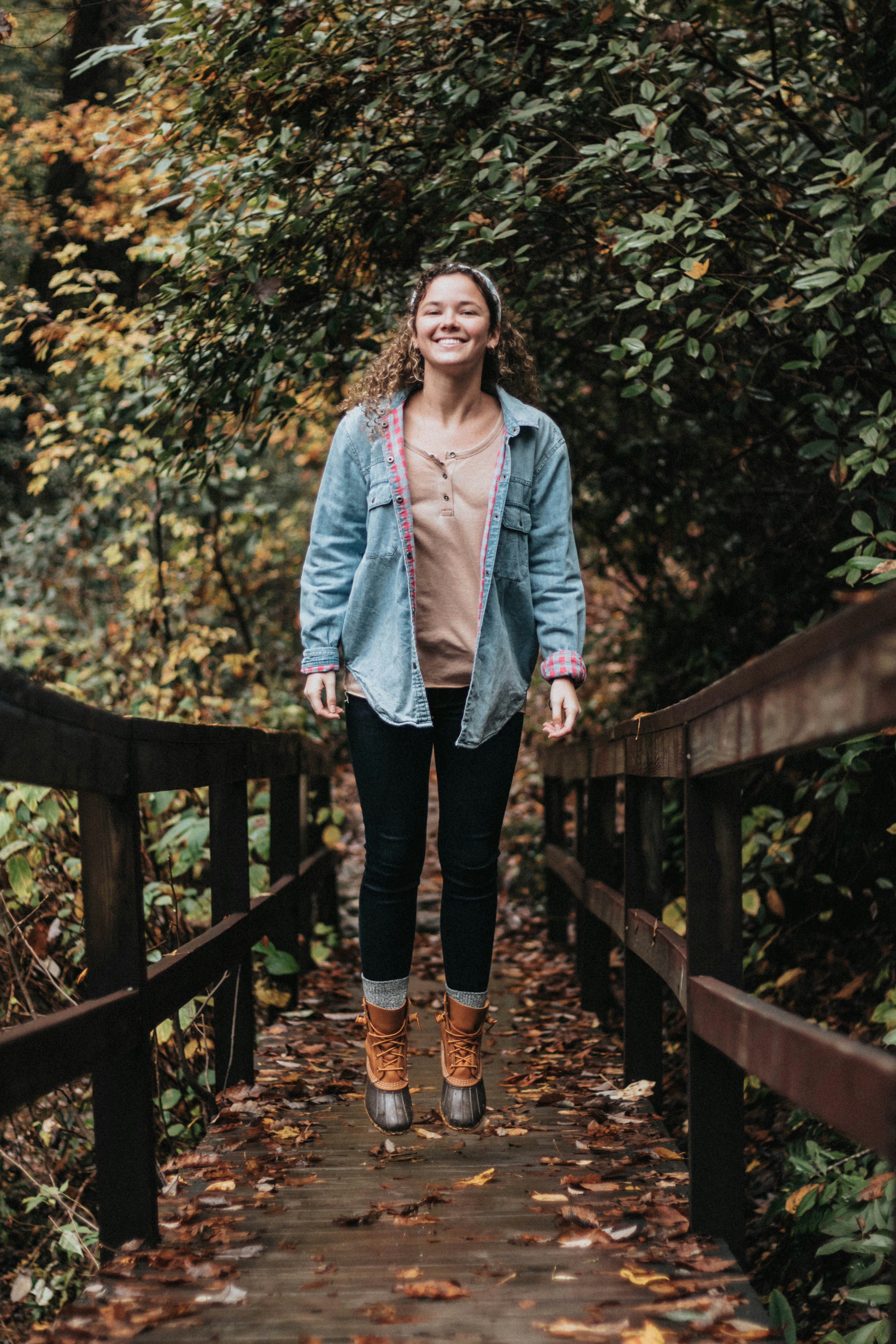 smiling woman standing on wooden bridge
