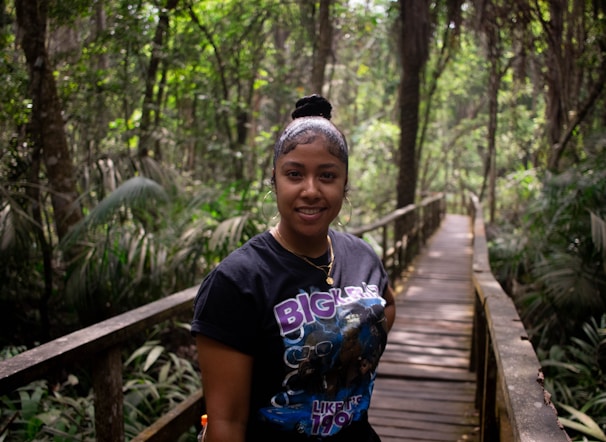 A smiling creator guiding travelers through a lush forest trail during an eco-adventure.