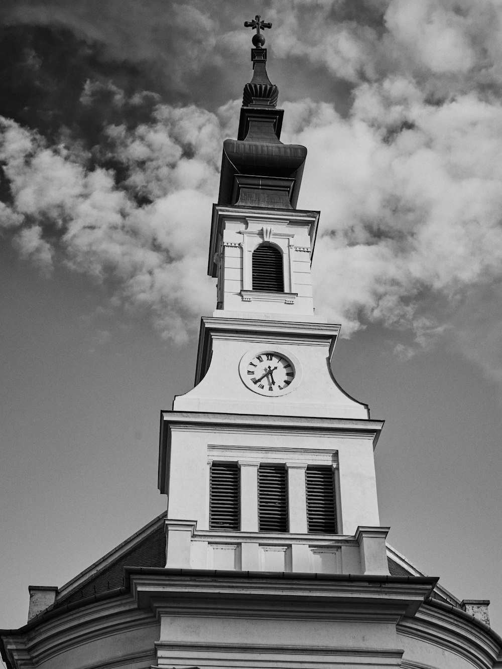 white clock tower across clouds grayscale photo