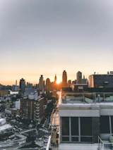 Close-up of hands exchanging documents over a backdrop of a city skyline at sunset.