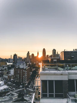 Close-up of hands exchanging documents over a backdrop of a city skyline at sunset.