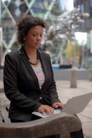 Business person coordinating a project on a laptop with urban background.