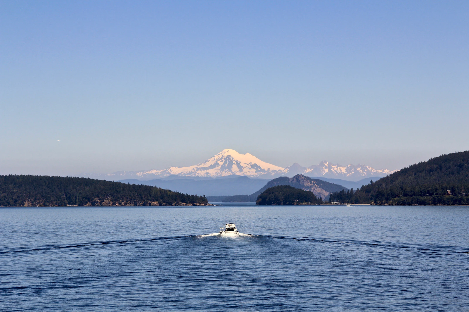 A boat crossing Puget Sound with evergreen islands and a snow-capped peak in the distance