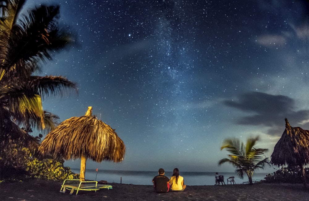 two person sitting near seashore