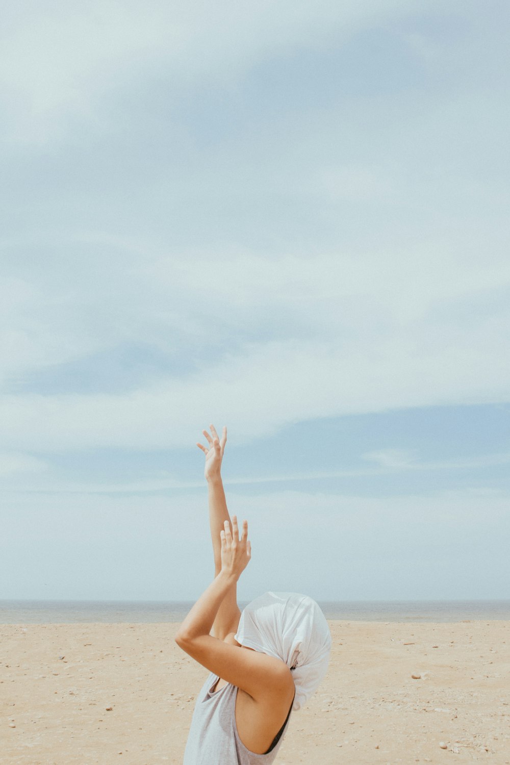 person rising both hands while covering face at daytime