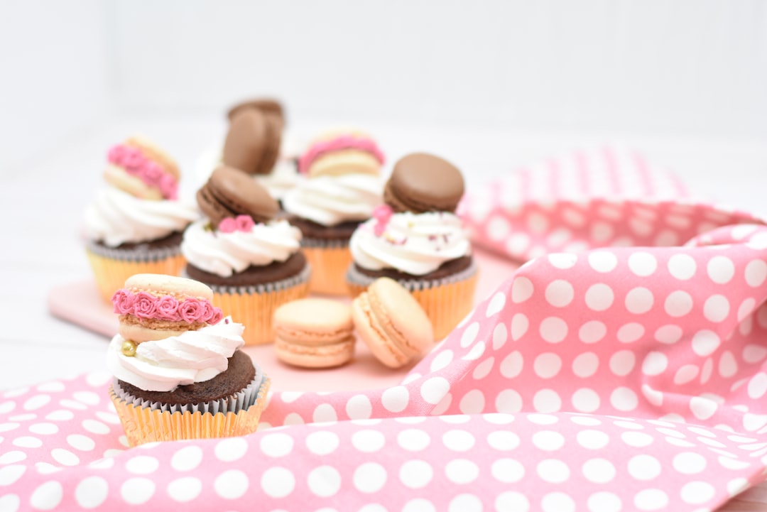 assorted macaroons and cupcakes on pink textile