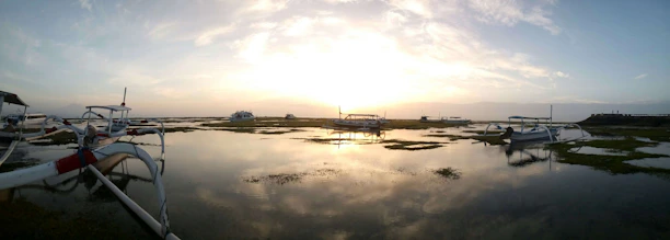 Golden sunset casting warm light over a tranquil Po Delta lagoon with traditional fishing boats.