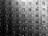 A symmetrical arrangement of metal lockers, each with a combination lock. The lockers have numerical labels and are organized in rows and columns, creating a repetitive geometric pattern. The image is in black and white, emphasizing contrasts and shadows.