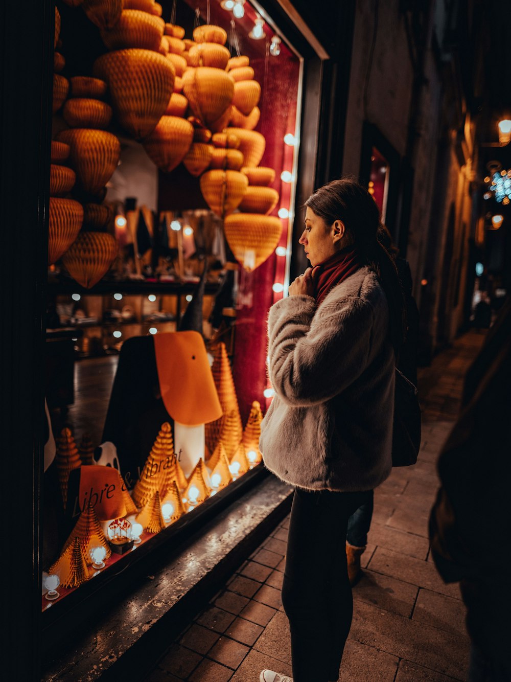 woman in gray jacket standing beside store