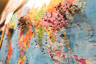 A world map densely populated with colorful pins, each indicating various locations across different continents. The focus is on the regions of Asia and parts of Oceania, with numerous pins clustered together, suggesting popular or significant places.