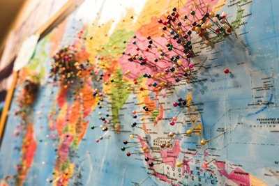 A world map densely populated with colorful pins, each indicating various locations across different continents. The focus is on the regions of Asia and parts of Oceania, with numerous pins clustered together, suggesting popular or significant places.