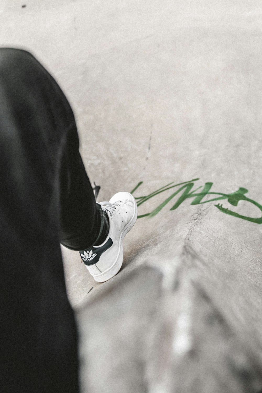 person wearing black pants and white Adidas shoe