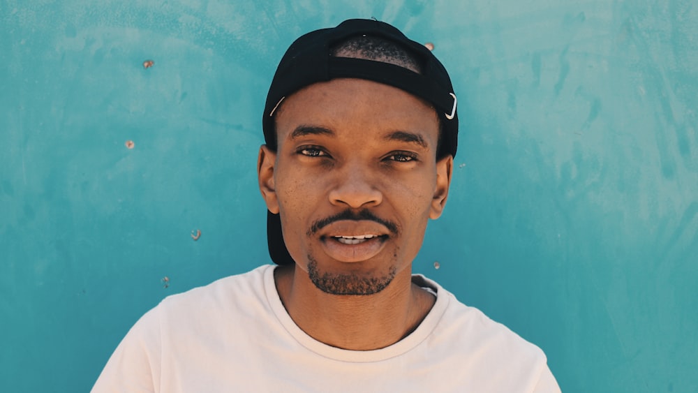 man in white shirt wearing black cap