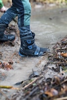 Close-up of boots splashing through a shallow stream during a hiking trail.