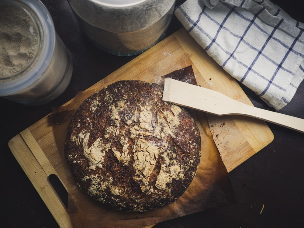 round baked pastry on brown wooden chopping board with wooden spatula