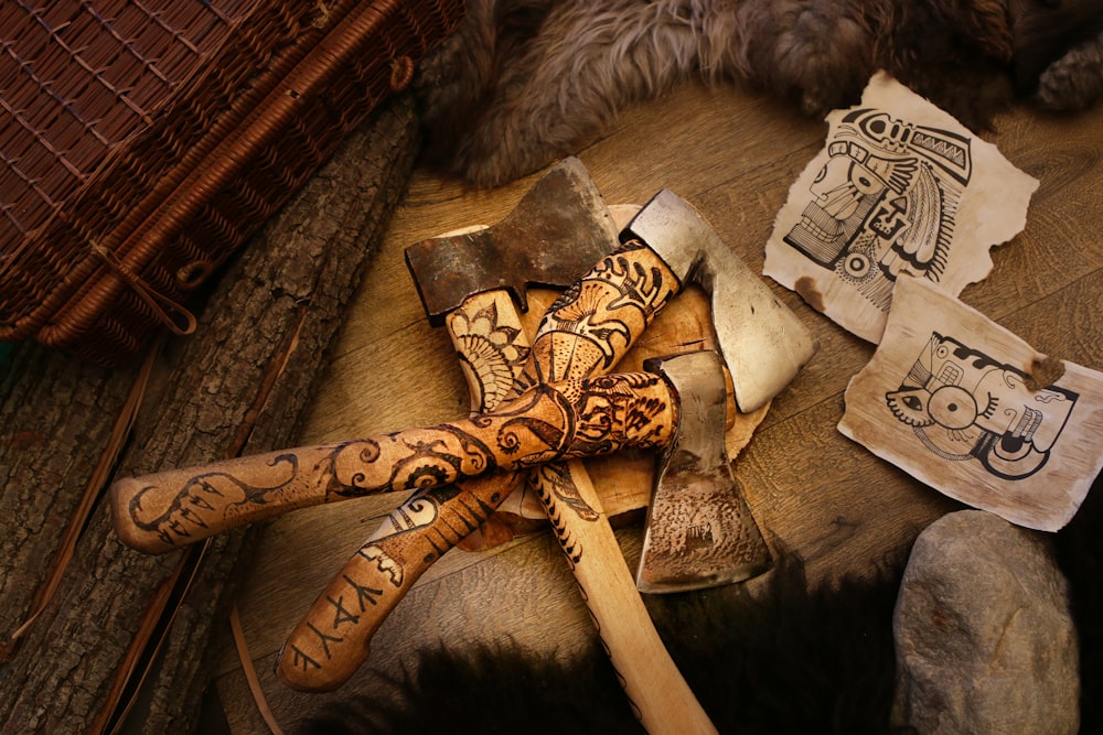 three brown handled axes on brown textile