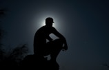 A silhouette of a figure standing under a full moon surrounded by mist.